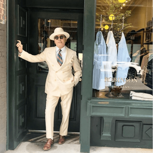 Robinson modeling a cream suit outside the shop door
