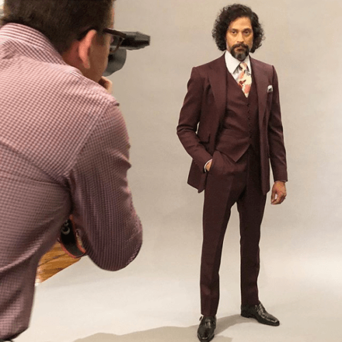Photographer taking a photo of a model showing off a brown three piece suit