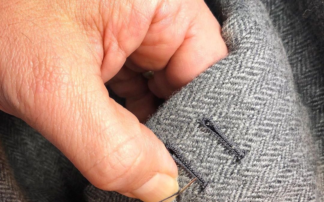 Closeup of a tailor stitching the button holes on a suit