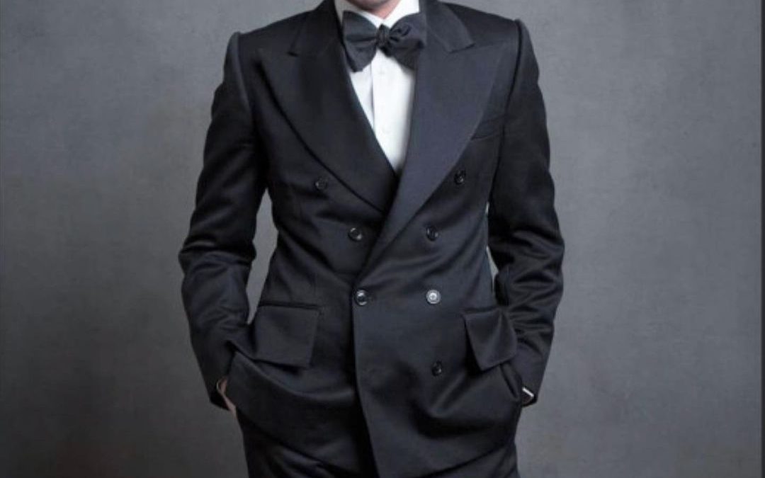 Model showing off a black suit with a black bow tie