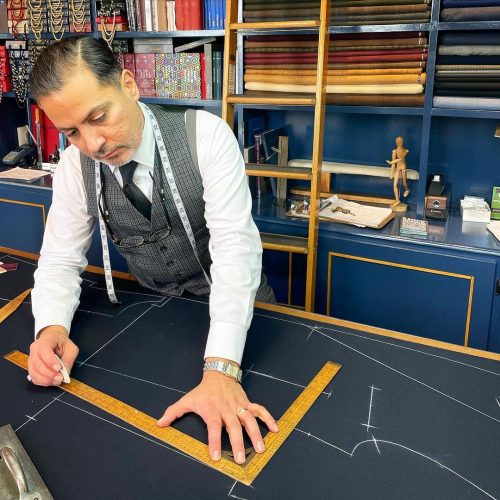 Tailor marking out a suit pattern on a new piece of cloth